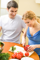 Young couple cooking together with vegetables at home