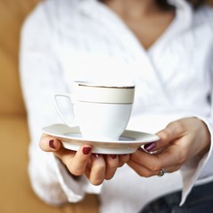 Junge Frau mit Kaffeetasse in den Haenden