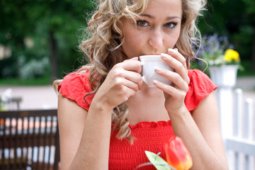 blonde lockige junge Frau mit Kaffeetasse