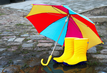 Gelbe Gummistiefel mit buntem Schirm