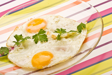 food series: fried eggs with parsley on the glassy plate