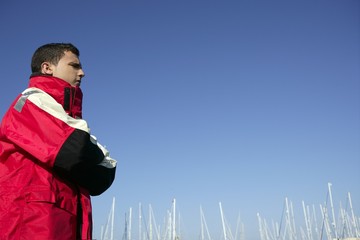 Handsome boy on harbor with red marine coat