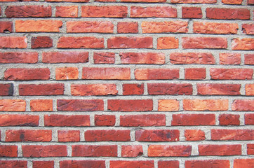 A close up of a red brickwall wtih grey plaster