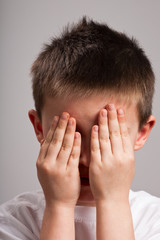 Little boy covering face with hands