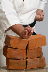 karate man breaking three bricks on white background