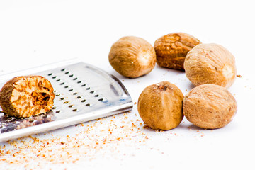 Several nutmegs with grater and fresh shavings