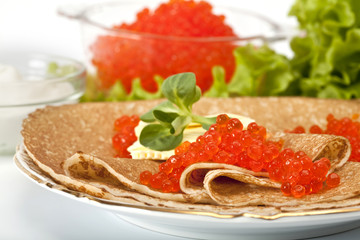 served place setting: pancake with red caviar, sour cream and gr