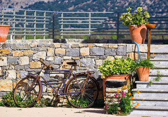 Fototapeta na wymiar Old bicycle against stone wall and flowers in pots