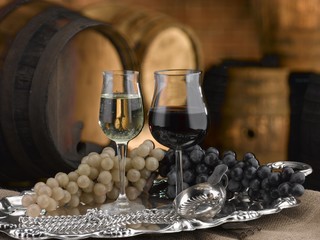 Red and white wine stem glasses. Grapes and barrels are in the background - obrazy, fototapety, plakaty
