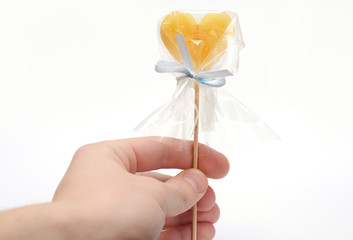 Hand gives heart-shaped candy isolated