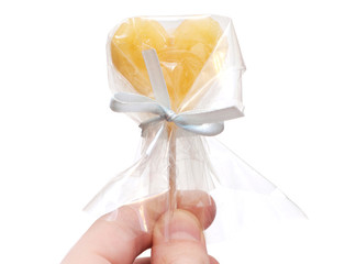 Hand gives heart-shaped candy closeup isolated