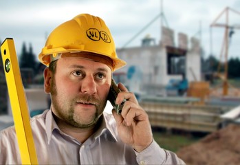 Baurbeiter telefoniert auf der Baustelle mit Wasserwaage