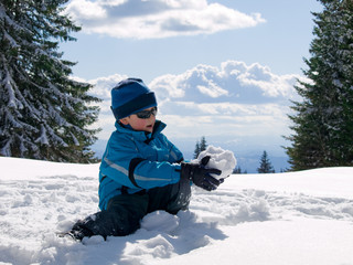 Fototapeta na wymiar boy playing in the snow on the mountain