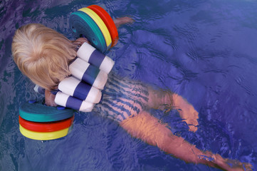 Kleinkind mit Schwimmhilfen im Pool