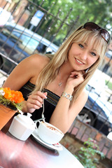 Blondine im Cafe mit Sonnenbrille und Milchkaffee