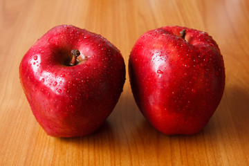 two fresh red apples on table