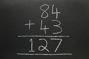 A basic addition sum written on a blackboard.