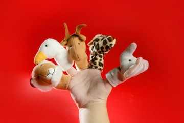 Finger puppets on a toddler hand over red