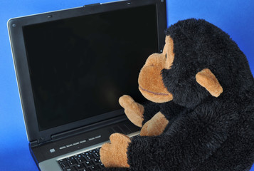 Close-up of a  stuffed monkey sitting on a portable computer