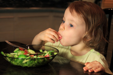 A girl eats vegetable salad.