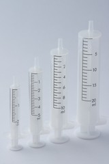 Four empty syringe barrels of increasing sizes
