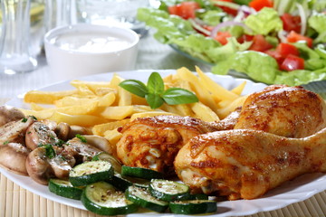Roasted chicken legs with chips and vegetables