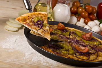 Piece of Pizza dish on wood floor with tomatos