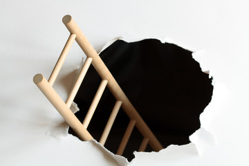 Wooden ladder inside black hole in white background