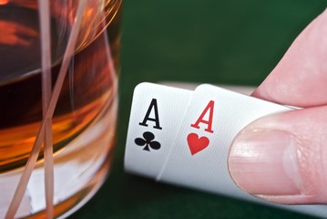 Showing two aces next to a whisky glass.