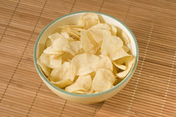 Potato chips in bowl on rattan background