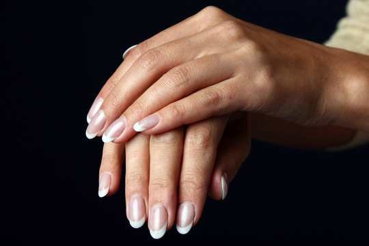 Beautiful woman hand with french manicure, isolated on black bac