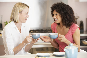 Obraz na płótnie Canvas Female Friends Enjoying Tea And Cookies At Home