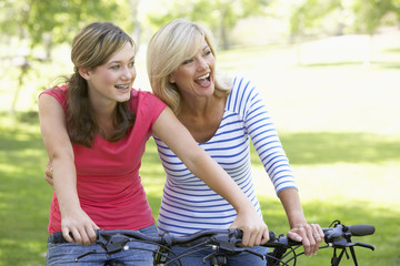 Mother And Daughter Cycling Through A Park