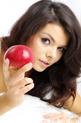 Portrait of  woman sitting on bed and eating fresh red apple