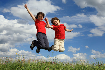 Kids jumping, running against blue sky