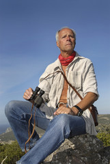 Naklejka na ściany i meble Mature man explorer posing outdoors with is binoculars