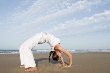 Frau macht Yoga am Strand