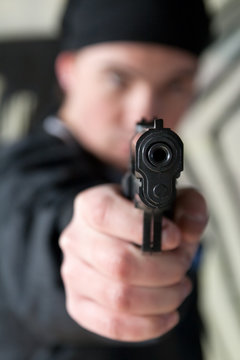 Young man pointing a gun straight at the camera