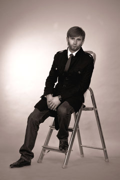 young man sitting on small stairs with hands crossed apear