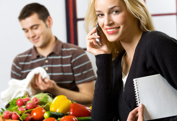 Young happy businesswoman on cellphone at kitchen