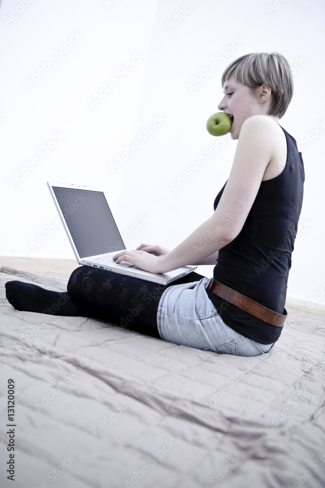 Poster junge frau sitzt auf boden mit laptop und apfel