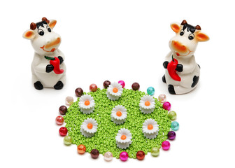 Two ceramic cows on the improvised meadow from beads