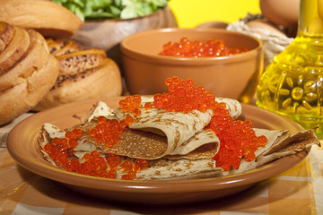 served place setting: pancake with red caviar and baked goods