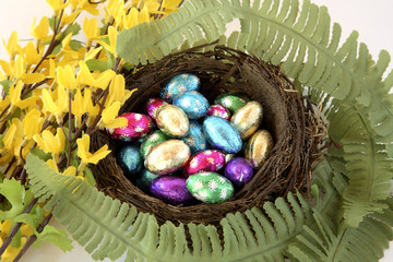 Birds nest of foil wrapped chocolate eggs with flowers.