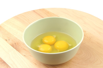 three raw broken eggs inside bowl