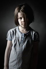 Low Key Shot of a Sad Little Girl against Grey Background
