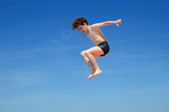 Boy jumping against blue sky