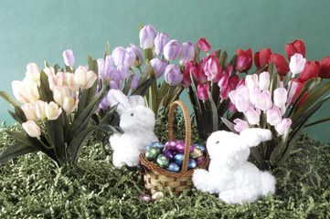 Two white bunnies with basket of eggs.
