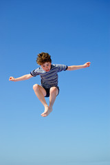 Fototapeta premium Boy jumping against blue sky