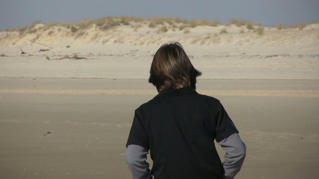 adolescent marchant sur la plage de dos